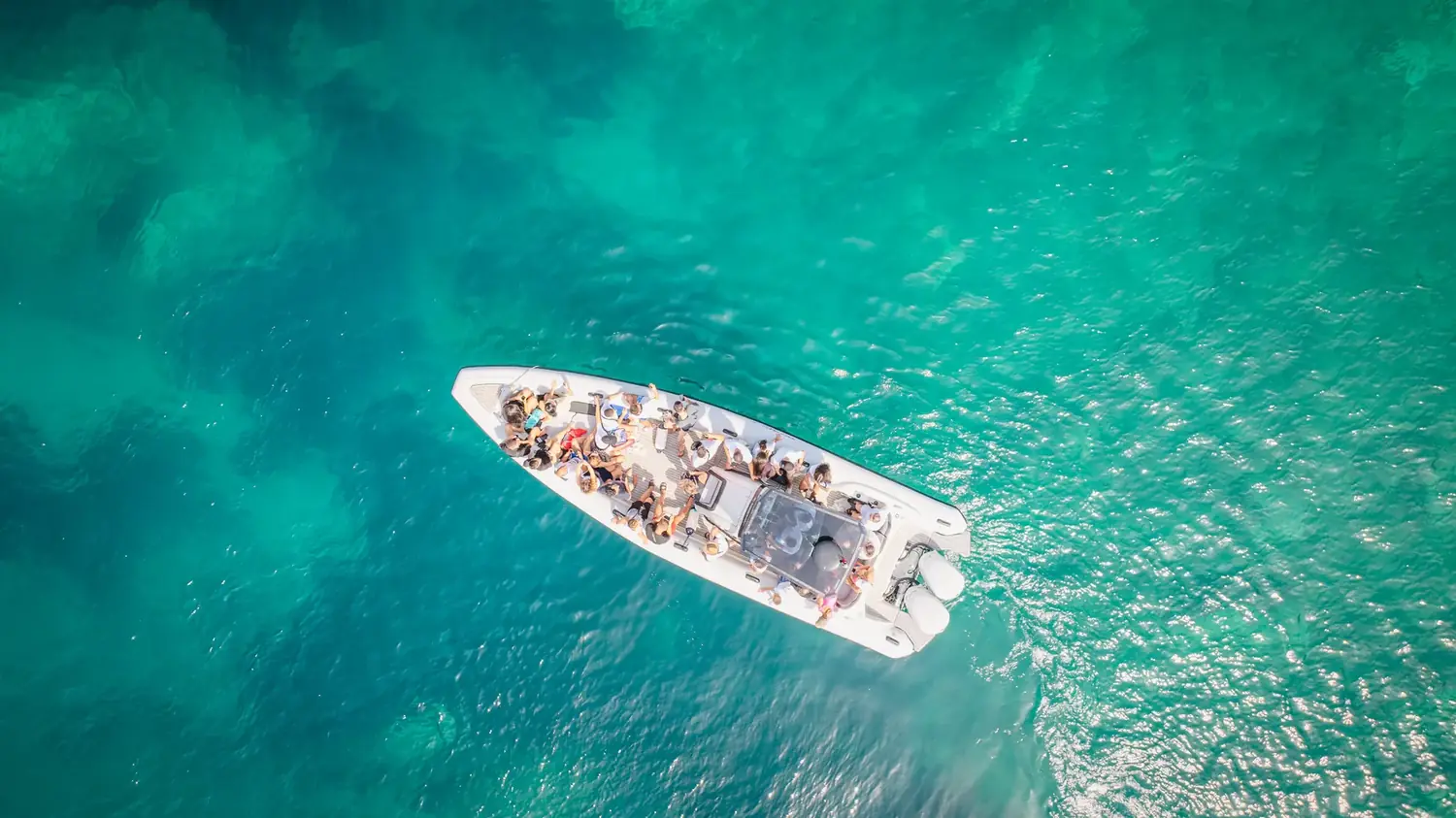 Top-down aerial of the Beast Boat full of guests in bright emerald water