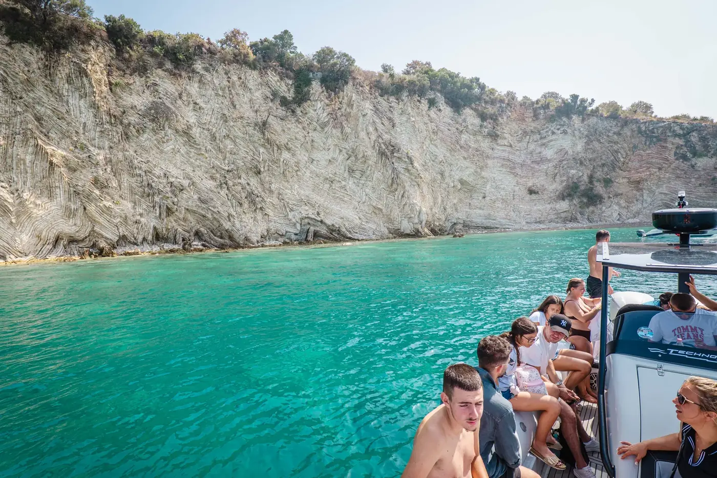 Guests on the Beast Boat looking out at white cliffs as it enters a turquoise cove
